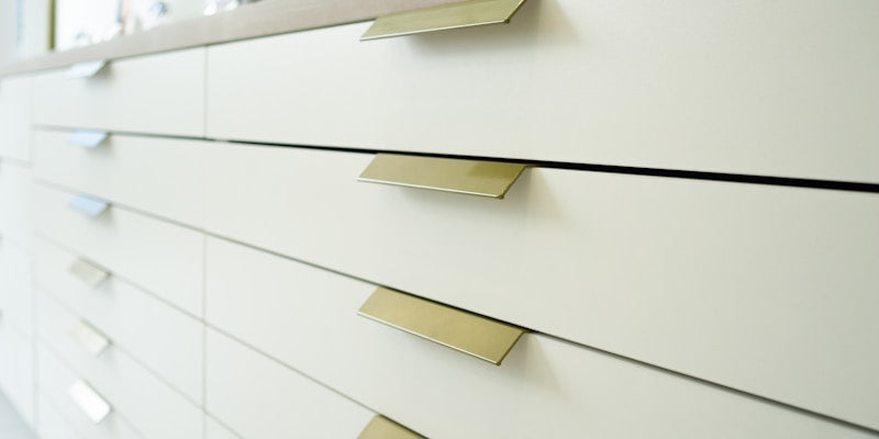 a close up of a white dresser with brass handles