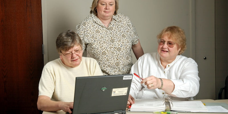 woman in white cardigan sitting beside woman in black and white floral shirt