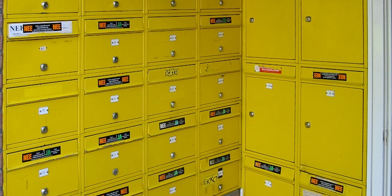 a bunch of yellow mail boxes sitting next to a brick wall