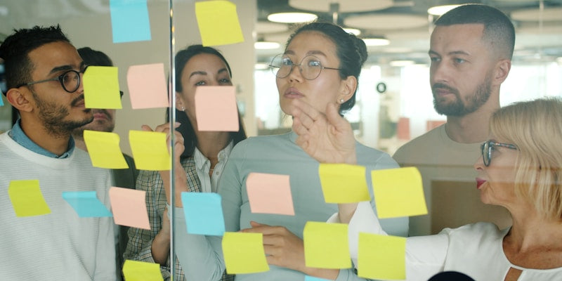 Diverse team collaborating on sticky notes.